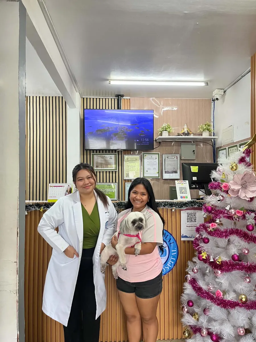 One of our vets with a client and her shih tzu at the front desk